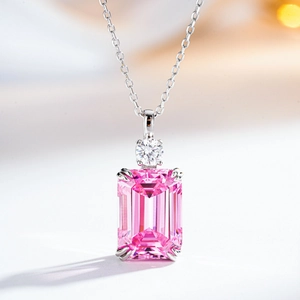 Macro shot of silver necklace with pink emerald-cut gemstone and round accent stone