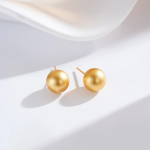 Close-up of matte gold spherical stud earrings with elegant brushed texture finish