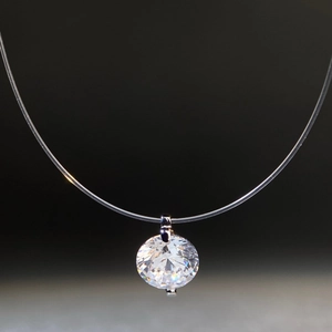 Macro detail of round moissanite pendant on transparent fish line nylon chain