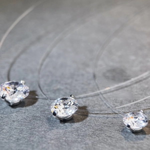 Detailed close-up of rose-cut aquamarine moissanite pendants on invisible fish line chains