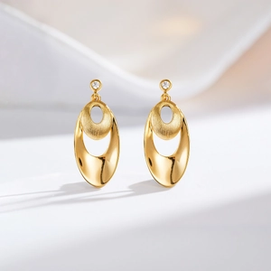 Detail of 24K gold earrings featuring double oval layers and brushed metal texture