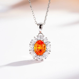 Macro detail of sunflower halo necklace with orange oval gem and white zircons