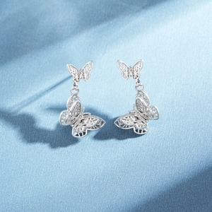 Silver 925 butterfly drop earrings with hollow weave design on light blue fabric