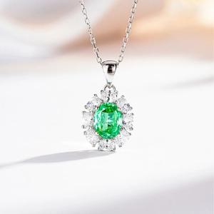 Detailed view of an oval emerald green gemstone pendant with a sparkling zircon halo