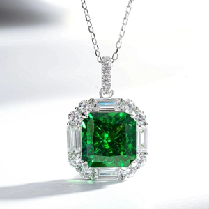 Close-up of radiant cut green emerald pendant with surrounding diamond halo on silver chain