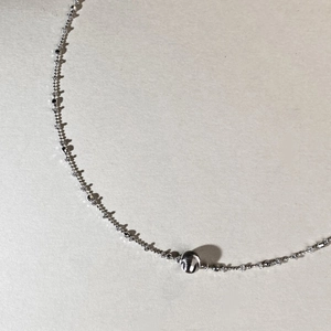 Macro shot of 925 sterling silver ball pendant necklace on textured grey surface