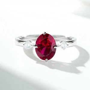Three-stone 925 silver ring featuring a large oval red ruby and clear zircon accents