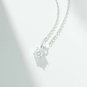 Detailed macro view of 1 carat round moissanite pendant with classic six-prong silver setting