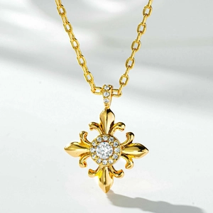 Macro detail of gold-plated fleur-de-lis cross pendant with shimmering white zircon stones