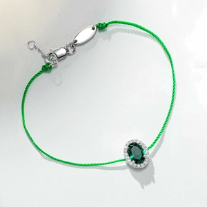 Détail du bracelet en corde verte avec pierre émeraude ovale entourée de petits diamants