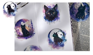 Artistic watercolor cat stickers with nebula patterns on a grid journal notebook page