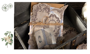 Vintage scrapbooking paper set with floral motifs and twine inside a wooden box