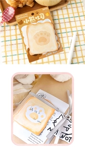 Detail of bread-shaped sticky notes with bear paw print on rustic checkered fabric