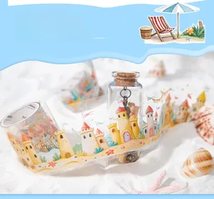 Close-up of decorative washi tape with ocean and castle themes on a sandy beach background