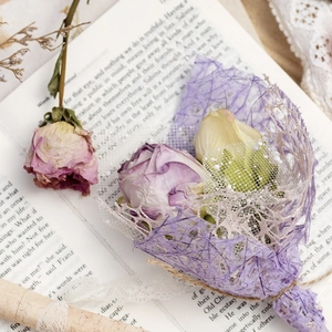 Vintage French style dried rose bouquet with lace wrapping and antique book background