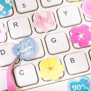 DIY colorful heart and flower stickers for journal decoration on a white laptop keyboard
