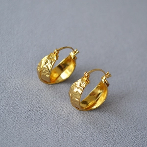 Macro detail of gold plated brass hoop earrings with vintage crumpled metal texture