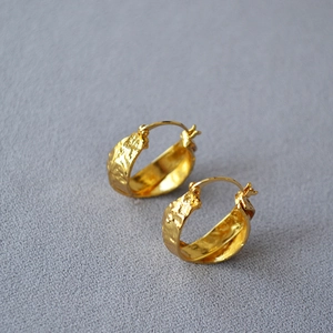 Detail of gold-plated hoop earrings featuring a unique hammered texture and vintage finish