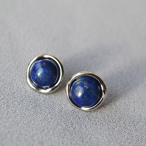 Minimalist lapis lazuli stud earrings with irregular silver edging on grey fabric