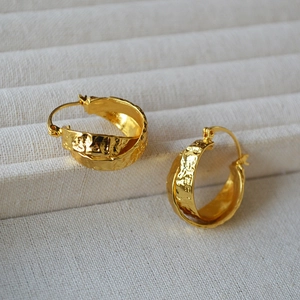 Detailed macro view of gold-plated brass hoop earrings with vintage hammered texture