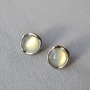 Detailed macro view of irregular silver opal stud earrings on a textured grey background