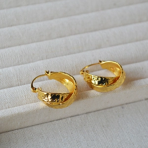 Macro shot of gold plated brass earrings featuring hammered texture and a vintage design