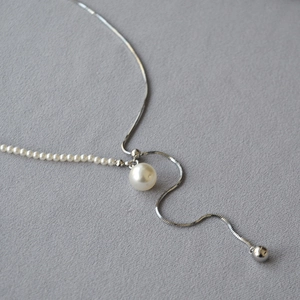 Detail of adjustable pearl and silver snake chain necklace with a large round pendant