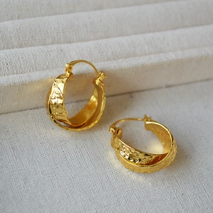 Detail of gold-plated brass earrings featuring a textured hammered finish and intertwined hoops