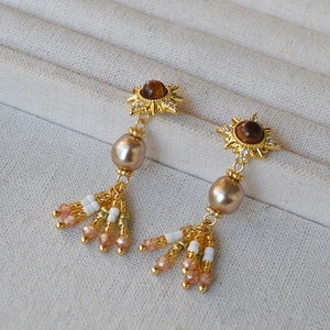 Dettaglio orecchini sole vintage con occhio di tigre e lunghe nappe di perline