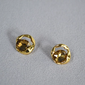 Detail of amber gemstone earrings with irregular gold-plated liquid metal design