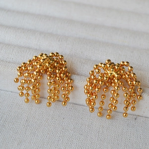 Macro shot of gold beaded chain tassel earrings with cascading fountain design