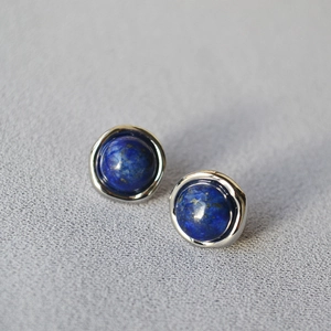 Detailed close-up of round lapis lazuli stud earrings with silver lace edge setting
