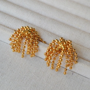 Close-up of golden beaded chain tassel earrings with floral fountain design