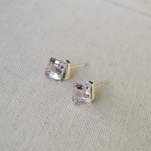 Close-up of geometric square pink crystal earrings with 925 silver studs on fabric