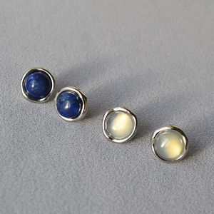 Macro detail of 925 silver round stud earrings inlaid with lapis lazuli and moonstone