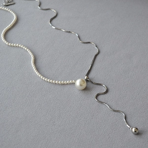 Macro detail of the pearl and silver snake chain connection with adjustable Y-necklace link