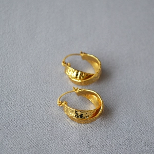 Detail of vintage gold-plated brass earrings with handmade hammered texture design