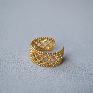 Macro shot of gold-plated adjustable ring featuring intricate hollow mesh weave patterns