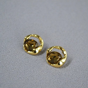 Detail of gold geometric irregular earrings with faceted amber champagne gemstones