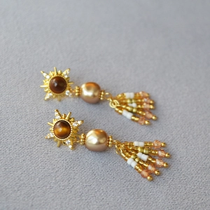 Dettaglio di orecchini vintage boho con nappe, pietra occhio di tigre e perno dorato
