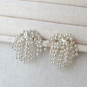 Detailed close-up of silver beaded tassel earrings on a soft fabric jewelry roll