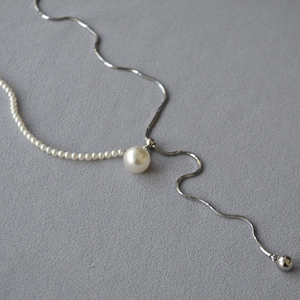 Detail of adjustable silver snake chain necklace with faux pearl stitching and polished bead