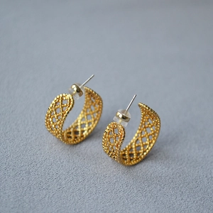 Detail view of gold hollow mesh C-shaped earrings with intricate filigree texture