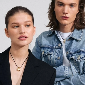 Close-up of minimalist gold teardrop pendant on black cord worn by models