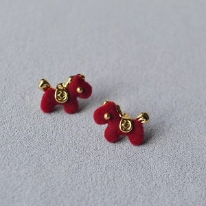 Detailed view of red flocked horse stud earrings with golden saddle and coin motif