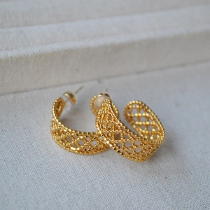Detailed macro view of gold-plated brass C-shaped earrings with hollow mesh texture