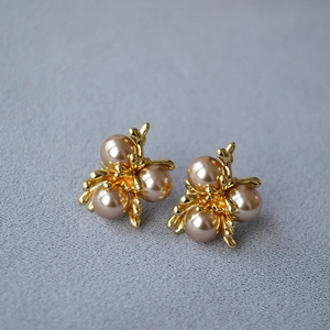 Macro view of French vintage champagne pearl earrings with gold floral branch setting