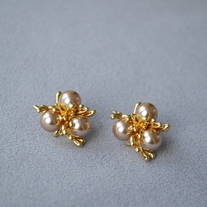 French vintage pearl stud earrings with gold floral accents on textured grey fabric