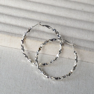 Polished silver irregular geometric textured large hoop earrings with shimmering faceted design