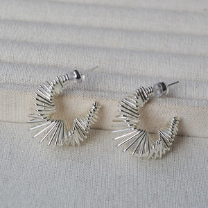 Gros plan sur des boucles d'oreilles argentées en C avec texture spirale filaire